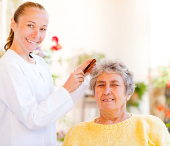 caregiver combing the hair of elderly woman